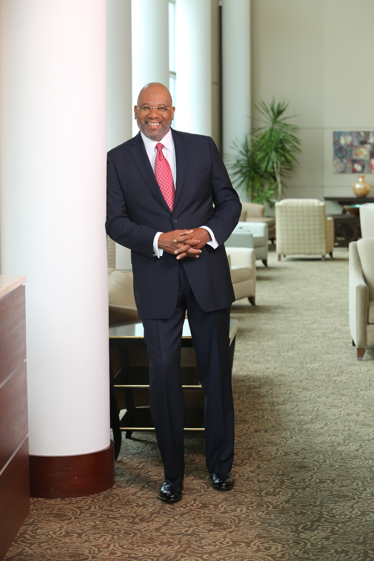 Home Ralph Douglas West in suit leaning on pillar